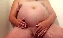 거대한 임신한 엄마가 샤워기 아래에서 섹시하게 자위하는 모습