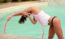 Pacar remaja berkepang kaca berpose dengan hula hoop di kolam renang