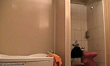Piękna kobieta relaksuje się pod prysznicem i jest obserwowana