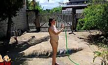 Uma dona-de-casa nudista toma um banho no pátio da frente